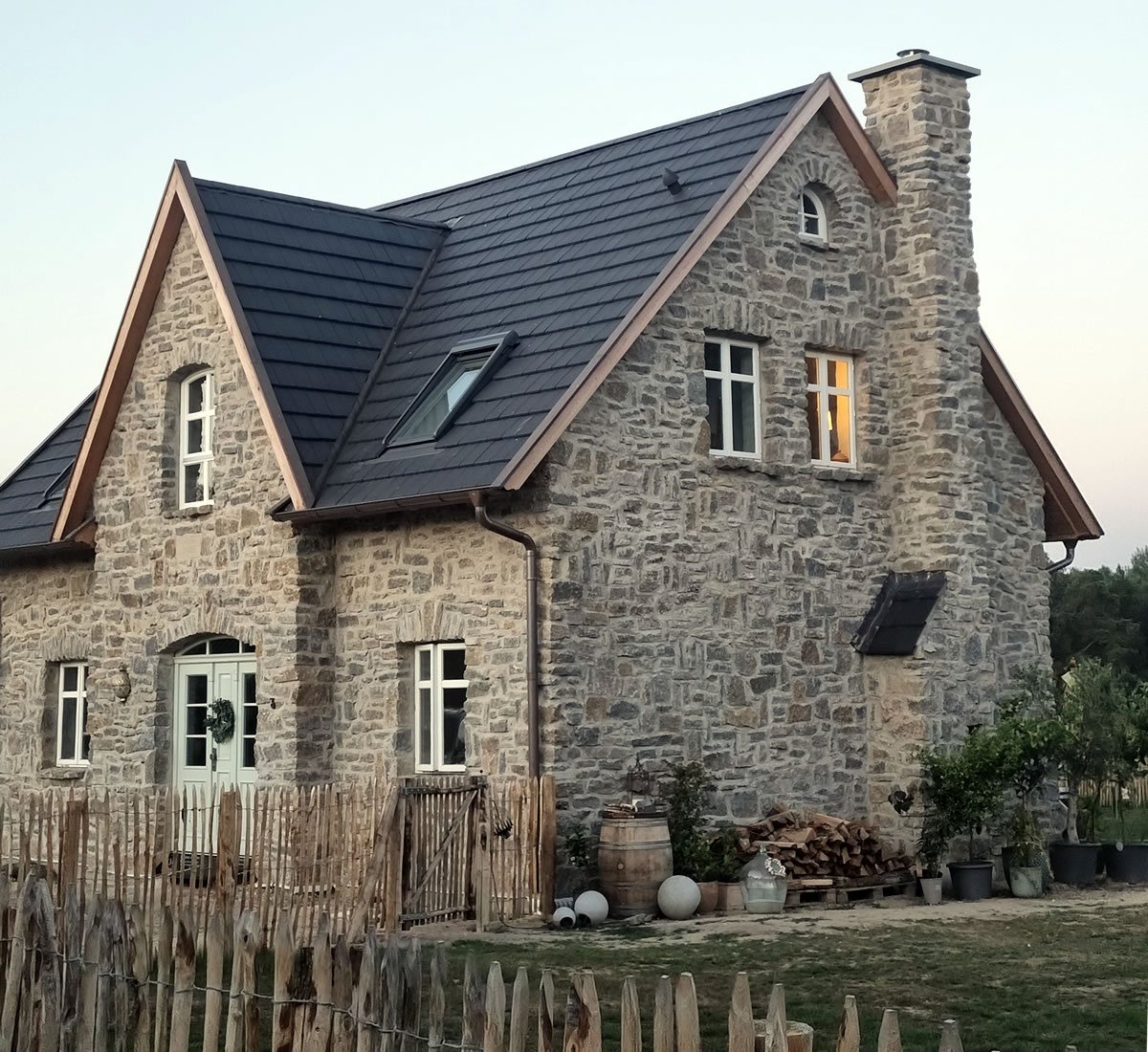 Vorderansicht eines englischen Cottages mit Hauseingang, Staketenzaun und Schornstein