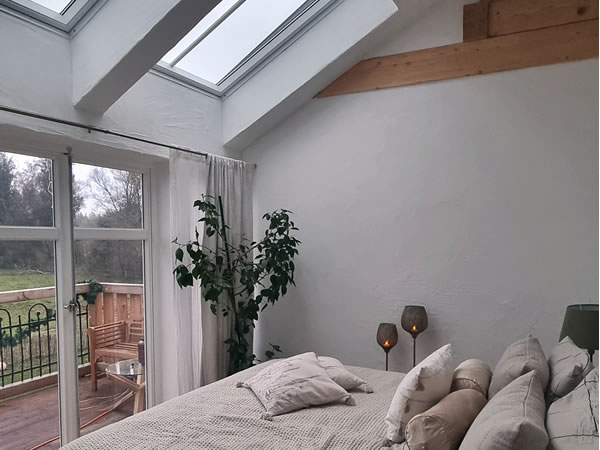 Schlafzimmer eines englischen Cottages mit Dachfenstern und Balkontür