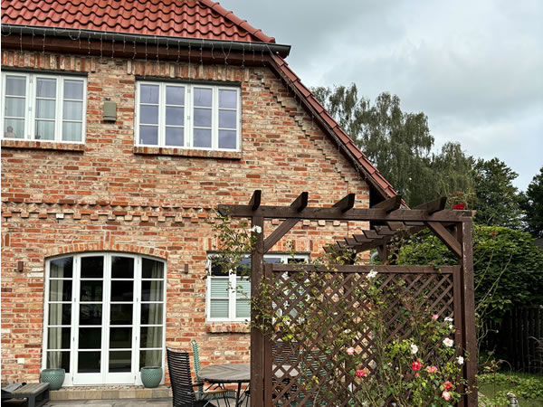 Das Holz der Pergola und des Krüppelwalmdaches ist einheitlich - Englische Cottages aus Celle - Bauunternehmen Alan Berry