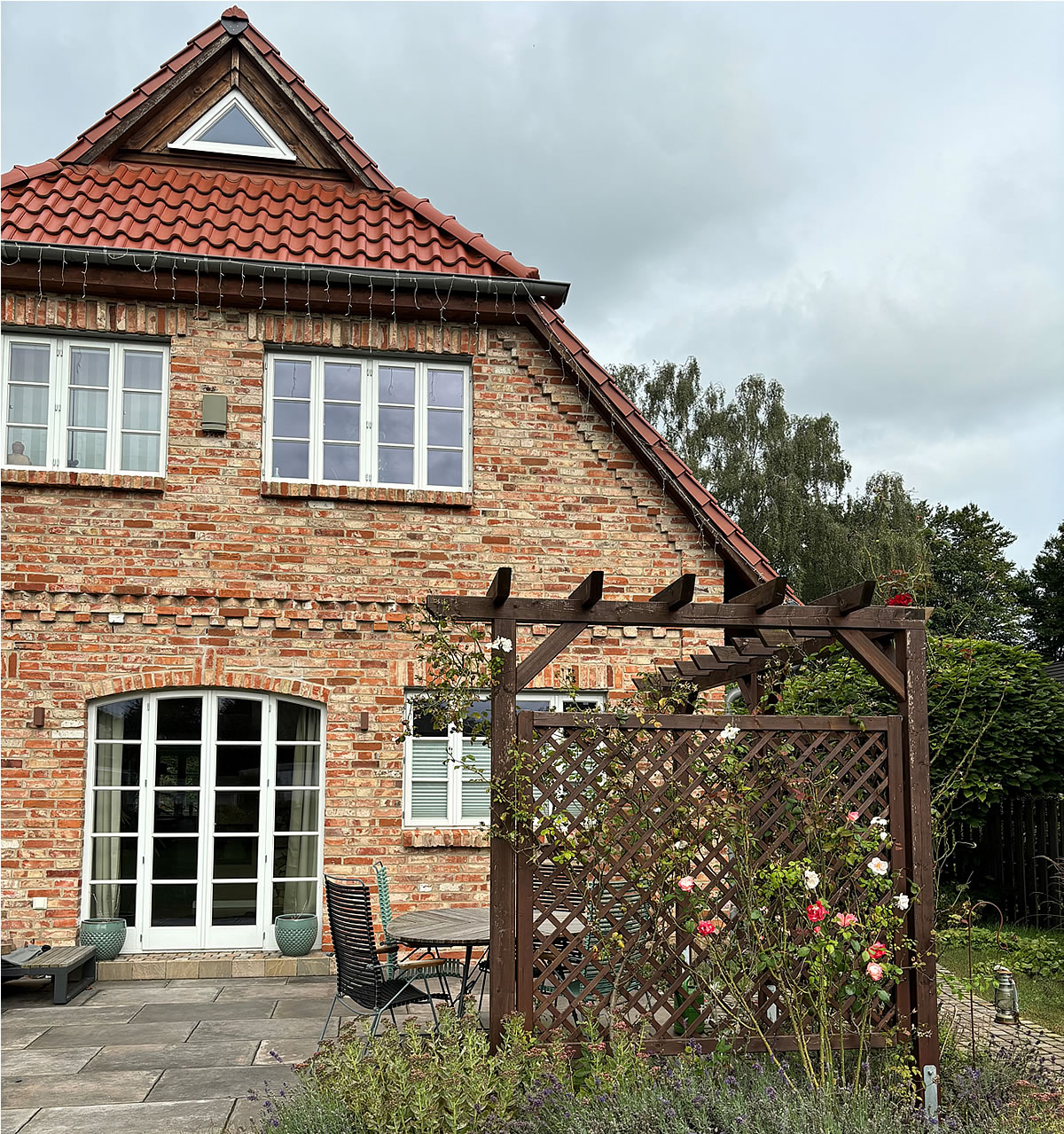 Das Holz der Pergola und des Krüppelwalmdaches ist einheitlich - Englische Cottages aus Celle - Bauunternehmen Alan Berry